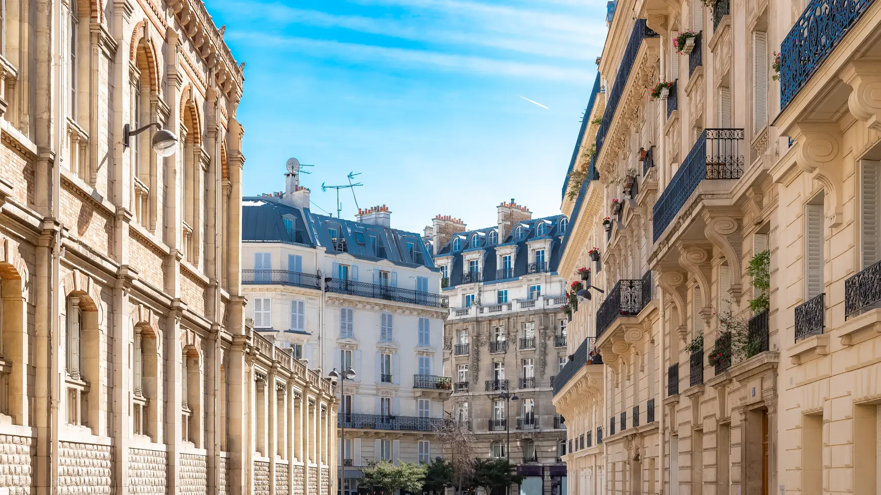 A sunlit Haussmann street in central Paris under a clear sky.